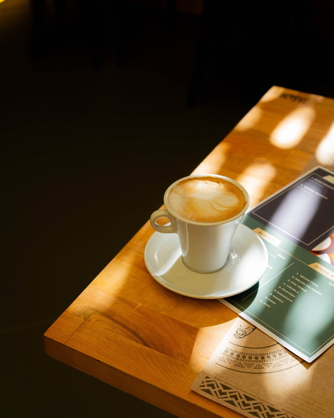 Café y carta de jugos naturales en una mesa de Taruka Bistró